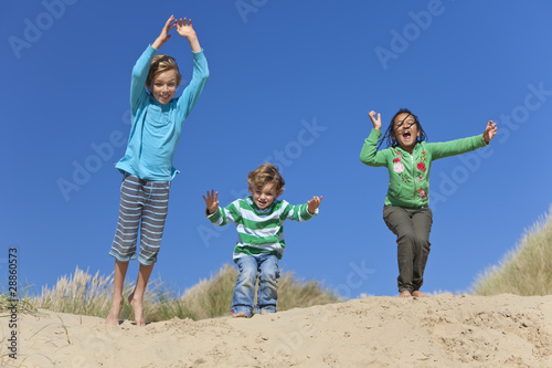Three Children Arms Raised Jumping Having Fun on Beach © Darren Baker