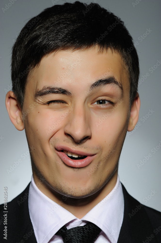 Portrait of funny young business man winking. expressions on gra Portrait of funny young business man winking. expressions on gra
