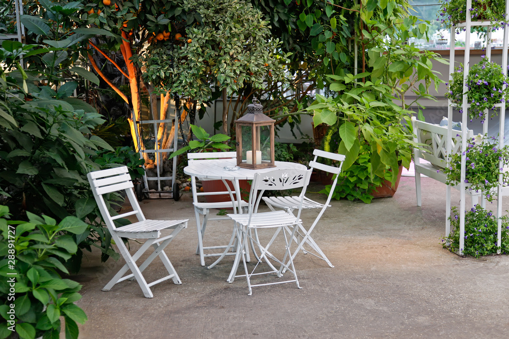 White table and chairs in beautiful garden.