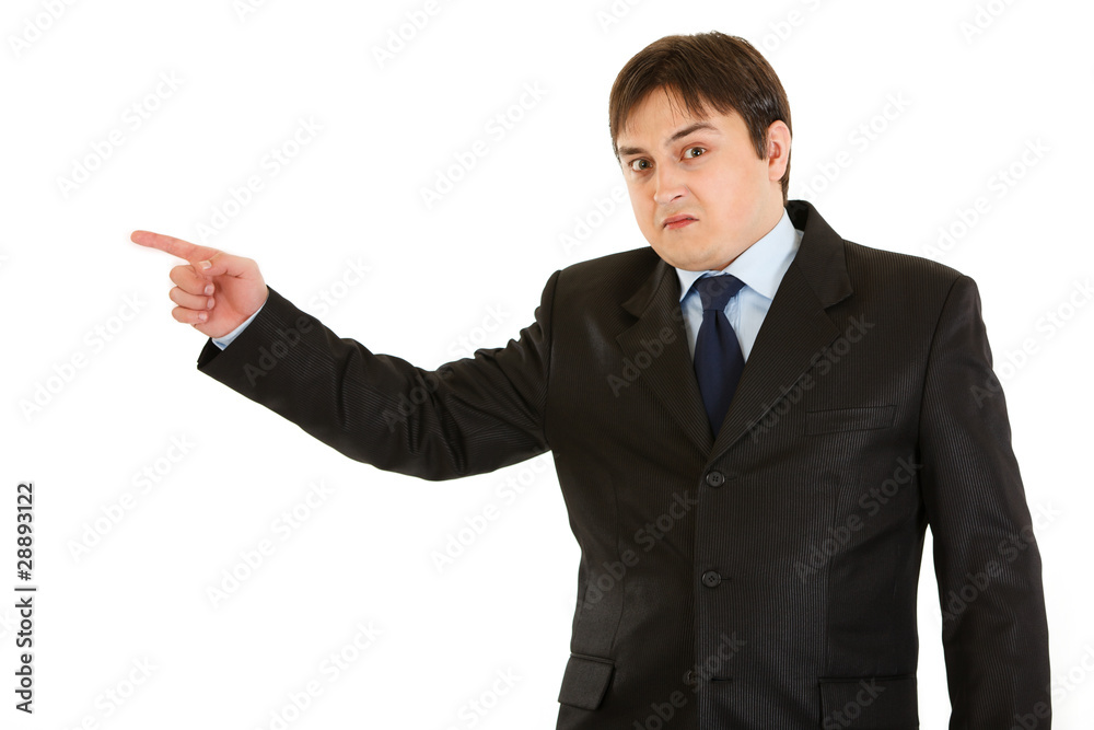 Shocked young businessman pointing finger in corner Shocked young businessman pointing finger in corner
