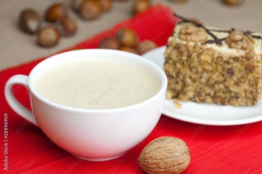 cup of cappuccino, a piece of cake with nuts on a plate lying on cup of cappuccino, a piece of cake with nuts on a plate lying on