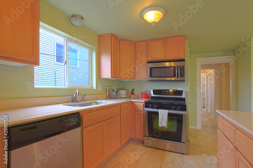 Green kitchen with maple cabinets and black appliances