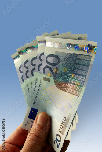 mano con banconote da venti euro su fondo azzurro photo