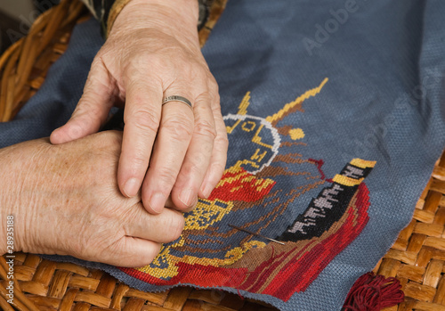 Old woman hand with a needle and a thread