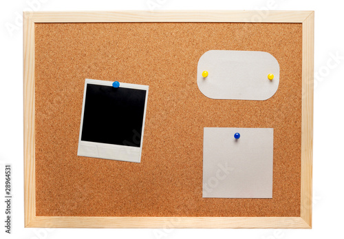 Blank instant photo and note papers on a cork board