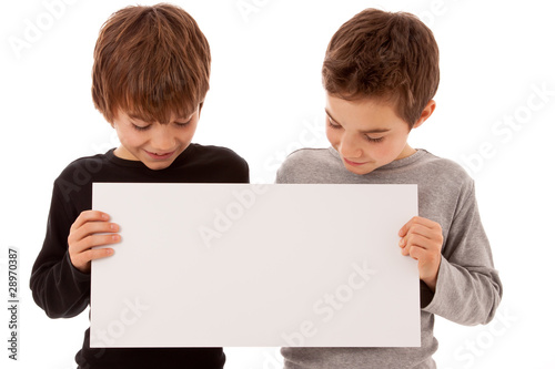 Zwei Jungen - Zwillinge halten ein weißes Schild