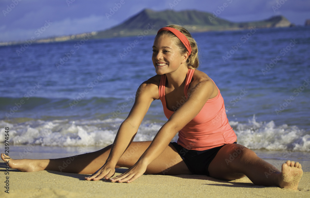young woman doing yoga and stretches on a beach in Hawaii