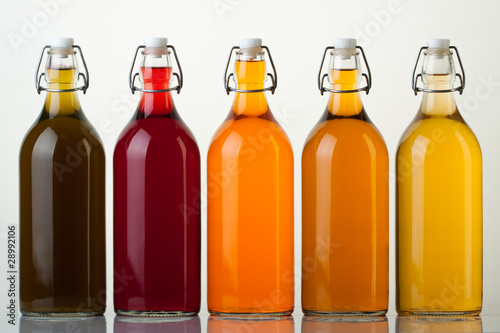 Five glass bottles with colored liquid on white background