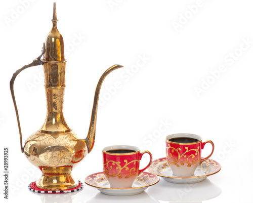 Arabic brass coffee pot with a welcoming  cups full of coffee.