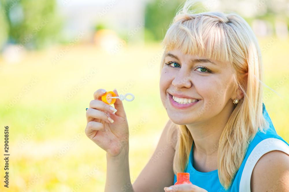 .Woman blowing bubbles in park .Woman blowing bubbles in park
