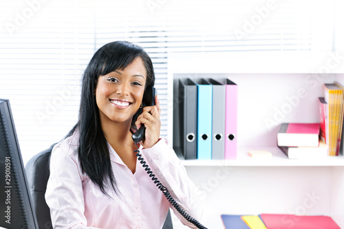 Smiling black businesswoman on phone at desk