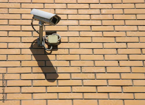 Security camera on yellow brick wall