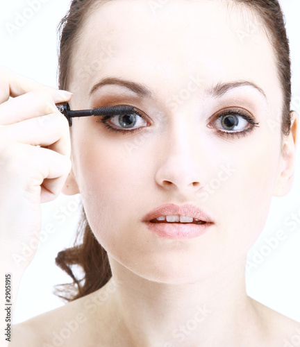 Portrait of pretty young woman applying mascara using