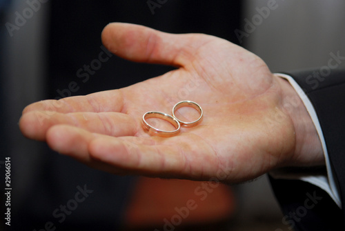 groom holding two gold wedding rings in palm