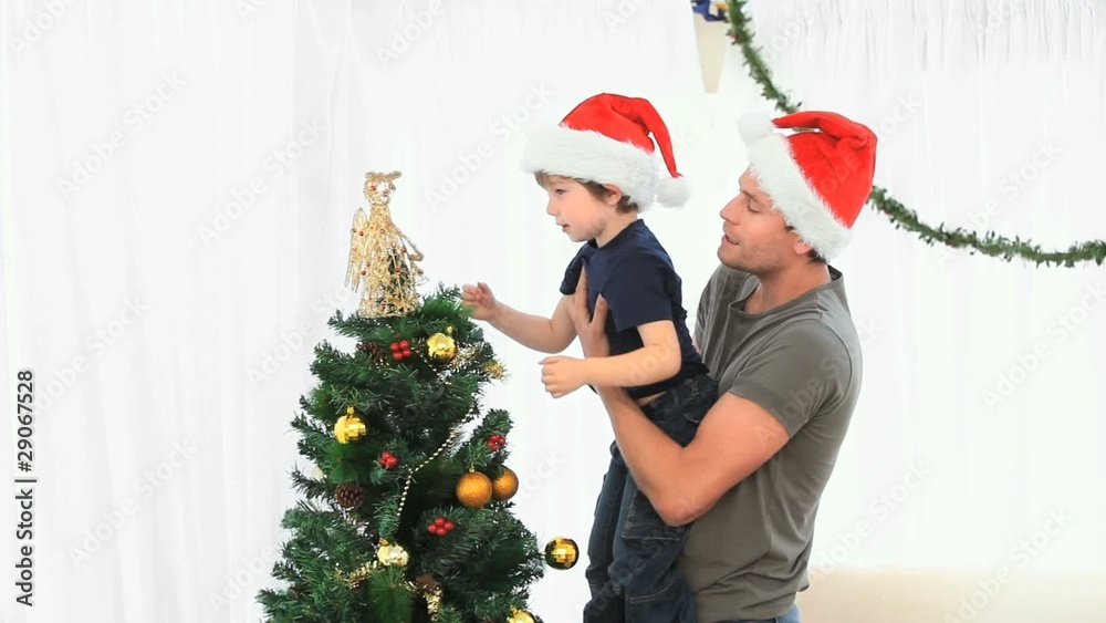 Father helping his son to decorate the Christmas tree Father helping his son to decorate the Christmas tree