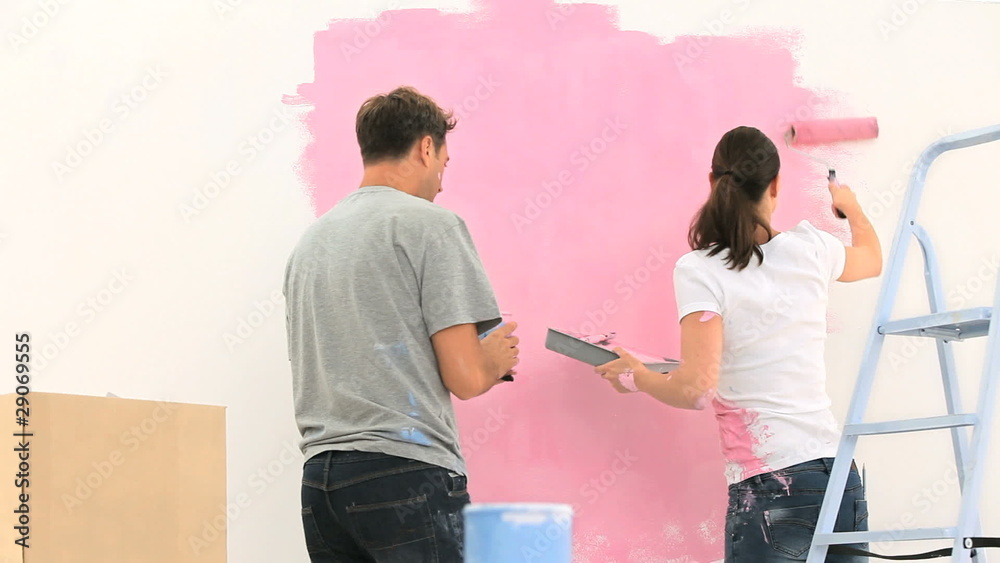 Couple painting a wall with the colour pink Couple painting a wall with the colour pink