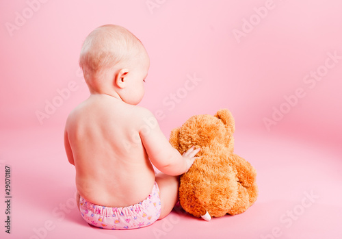 The small child with a bear cub on a pink background