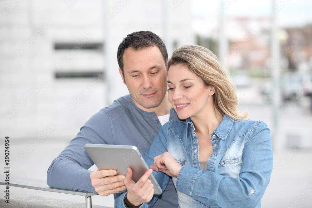 Couple using electronic tab in the street Couple using electronic tab in the street