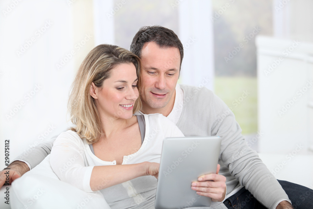 Couple sitting in sofa with electronic tab Couple sitting in sofa with electronic tab
