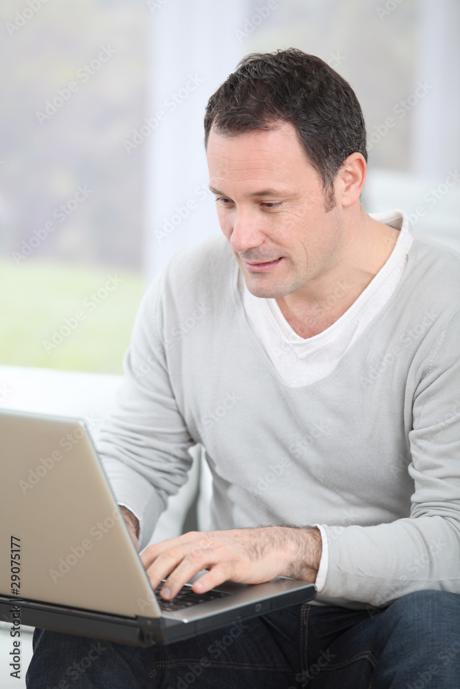 Man sitting in couch using laptop computer Man sitting in couch using laptop computer