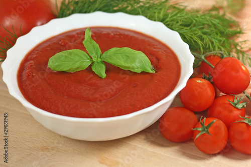 bowl of tomato soup garnished with basil leaves
