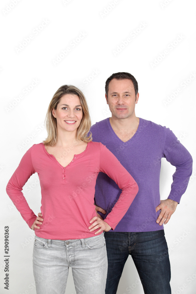 Couple standing on white background with hands on hips Couple standing on white background with hands on hips
