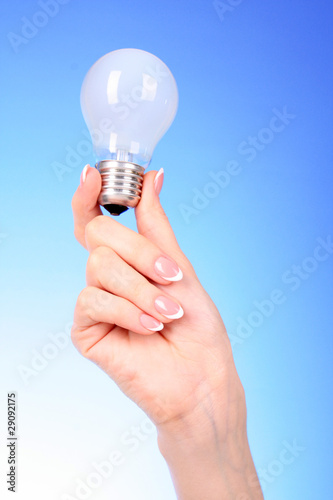 hand with lightbulb on blue background