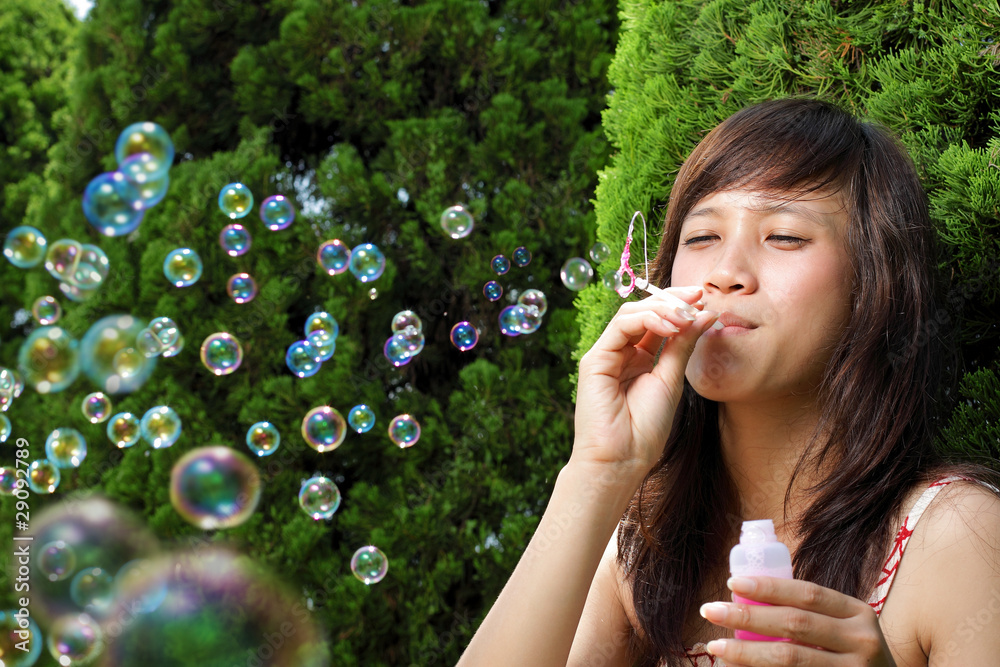 beautiful young woman playing with bubble in the garden