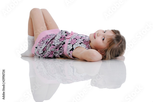 A beautiful little girl lying on the floor. Isolated on the whit