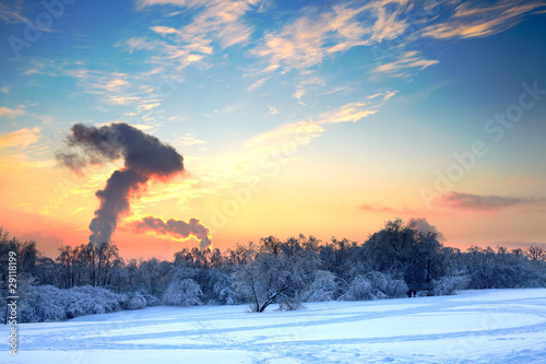 Idyllic winter landscape spoiled by factory smoke