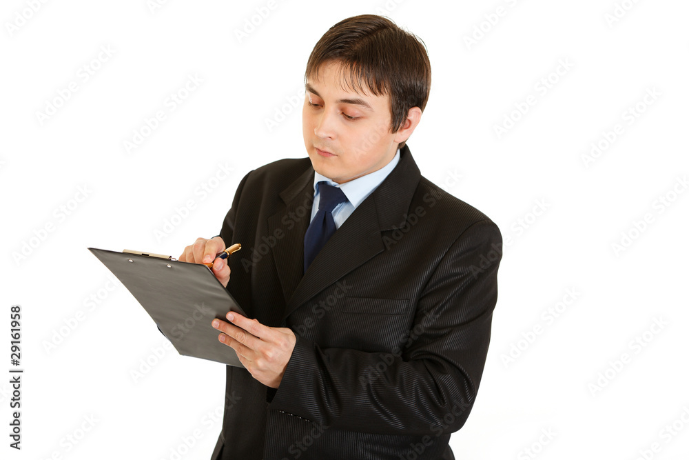 Serious young businessman making notes in document Serious young businessman making notes in document