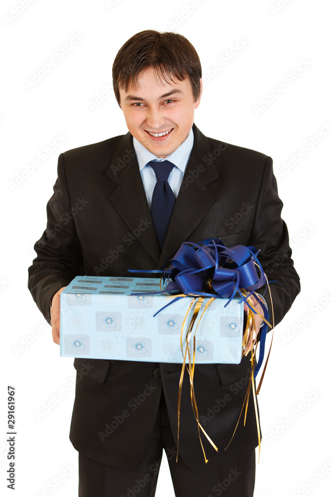 Laughing young businessman holding gift in hands isolated