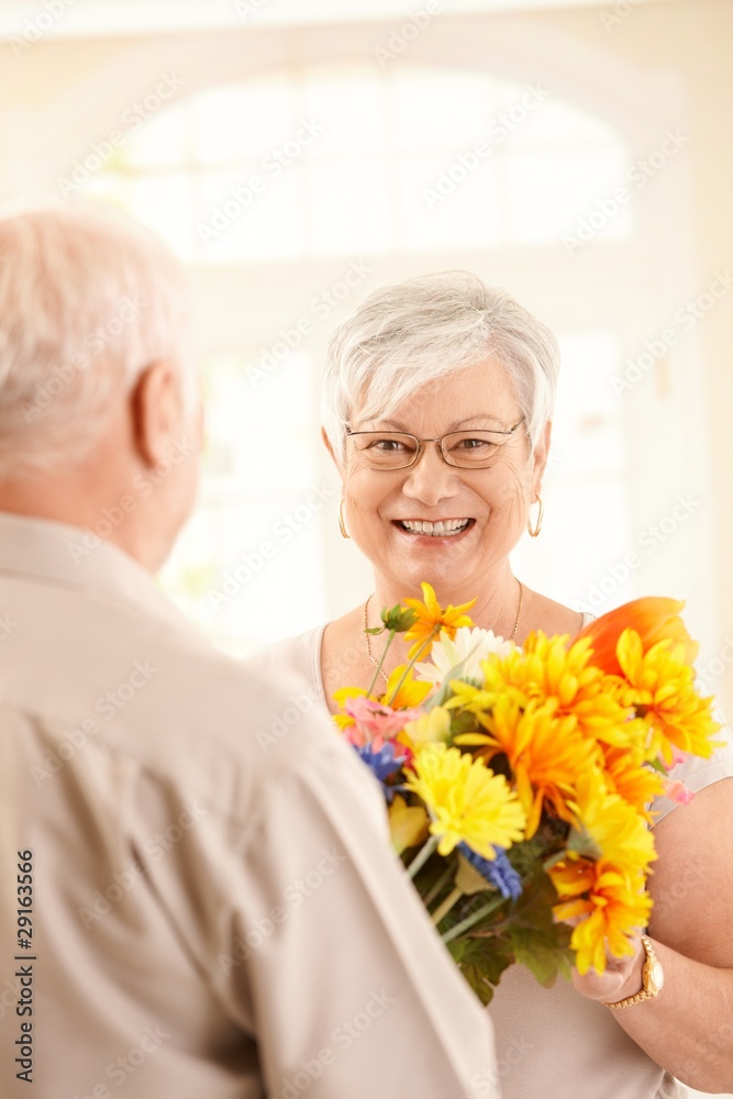 Laughing elderly woman getting bouquet