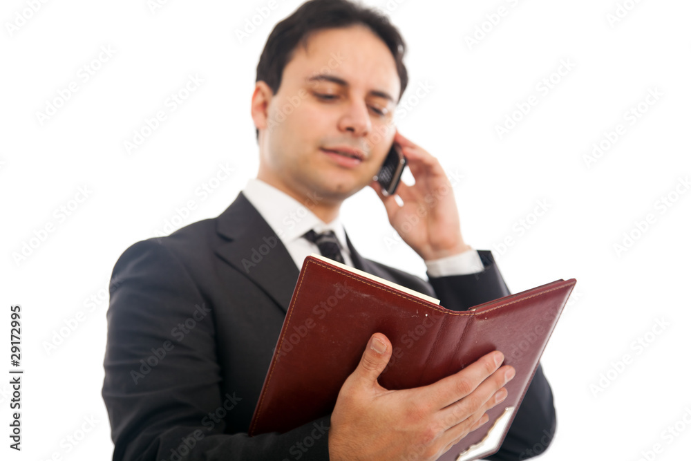 Businessman talking at the phone while holding his agenda Businessman talking at the phone while holding his agenda