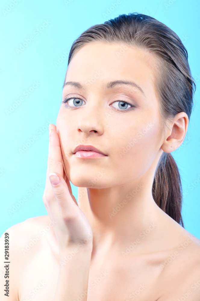 beautiful woman is touching her face, on blue background beautiful woman is touching her face, on blue background