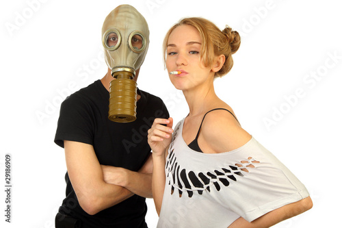 woman smokes on against the man in a gas mask