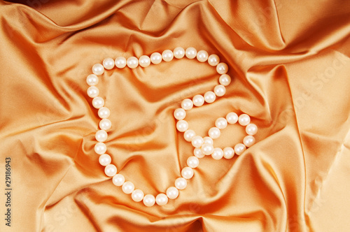 Pearl necklace on the bright satin background
