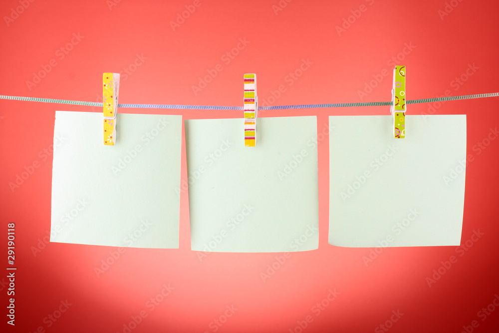 Blank paper sheets on a clothes line against the red background Blank paper sheets on a clothes line against the red background