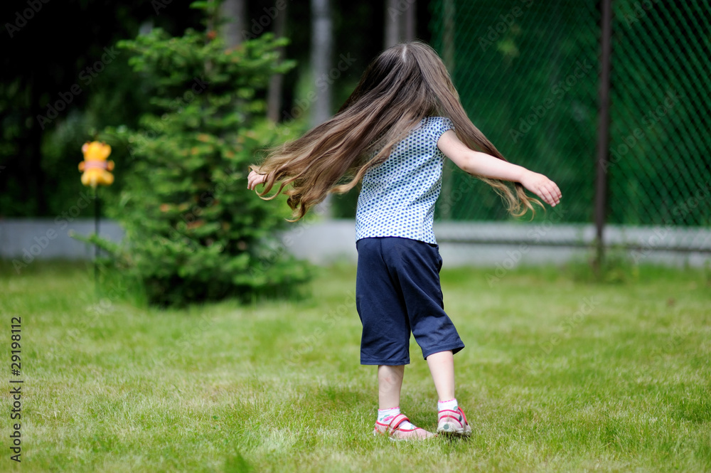 Adorable active little girl plays on backyard in spring Adorable active little girl plays on backyard in spring