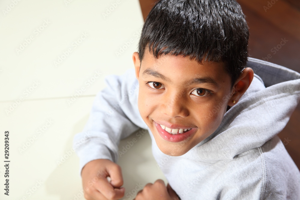 Young happy ethnic school boy 9 sitting in class