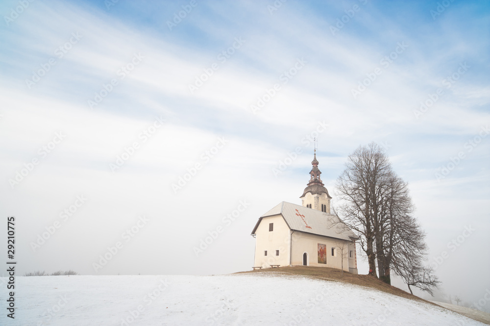 Small church on snowy hill. Slovenia, Skofja Loka area