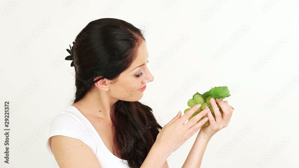 Young nice woman playing with and offering green grape cluster Young nice woman playing with and offering green grape cluster