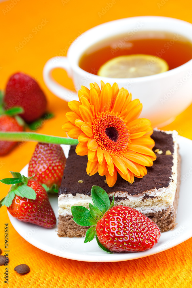 gerbera, lemon tea, cake and strawberries lying on the orange fa gerbera, lemon tea, cake and strawberries lying on the orange fa