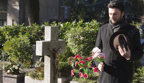 Mourning Man Standing on a Grave at the Cemetery