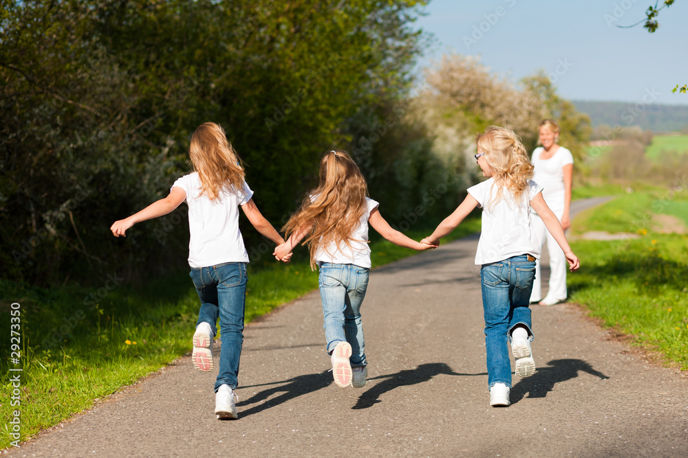 Fototapeta premium kids running down a path, mother standing