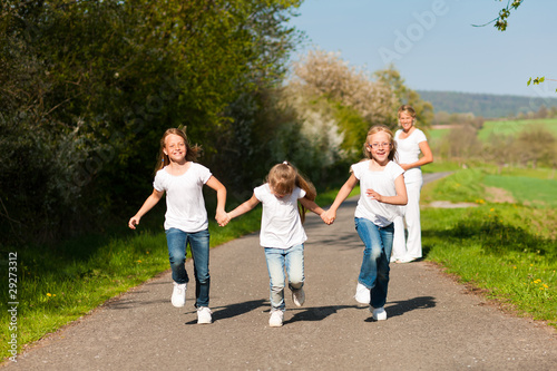 Kinder rennen auf Weg, Mutter in Hintergrund
