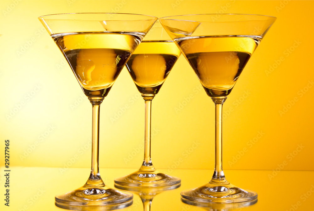 Three glasses of martini on a yellow background