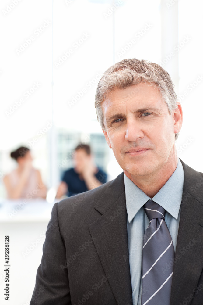 Fototapeta premium Businessman looking at the camera while his team is working