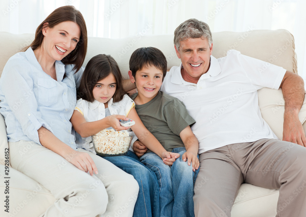 Family watching tv while they are eating popcorn Family watching tv while they are eating popcorn
