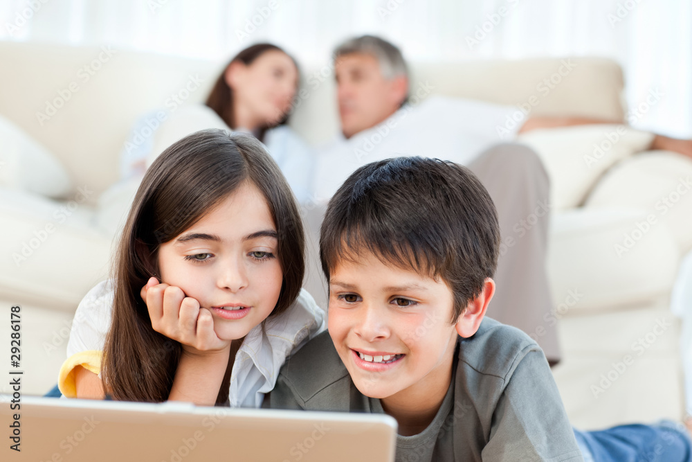 Lovely children watching a movie on their laptop at home Lovely children watching a movie on their laptop at home